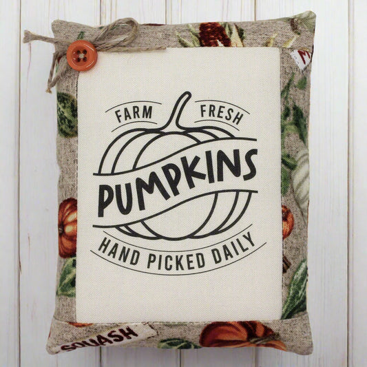 Decorative pillow tuck with pumpkin design and text on a wooden background
