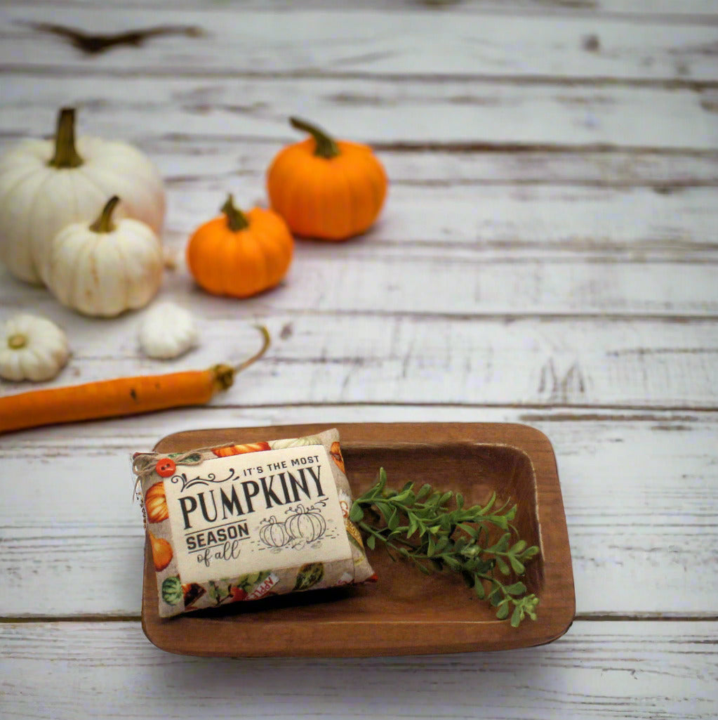 Mini pillow bowl filler on a wooden tray, surrounded by small pumpkins on a rustic wooden surface.