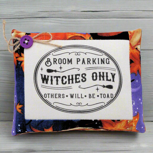 Decorative pillow with Halloween-themed text and colorful design on a wooden surface