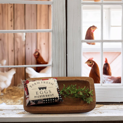 Wooden tray with 'Farm Fresh Eggs' sign and greenery, with chickens in the background.