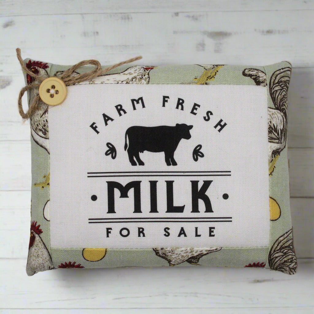 Decorative mini pillow with 'Farm Fresh Milk For Sale' text and cow illustration on a patterned background.