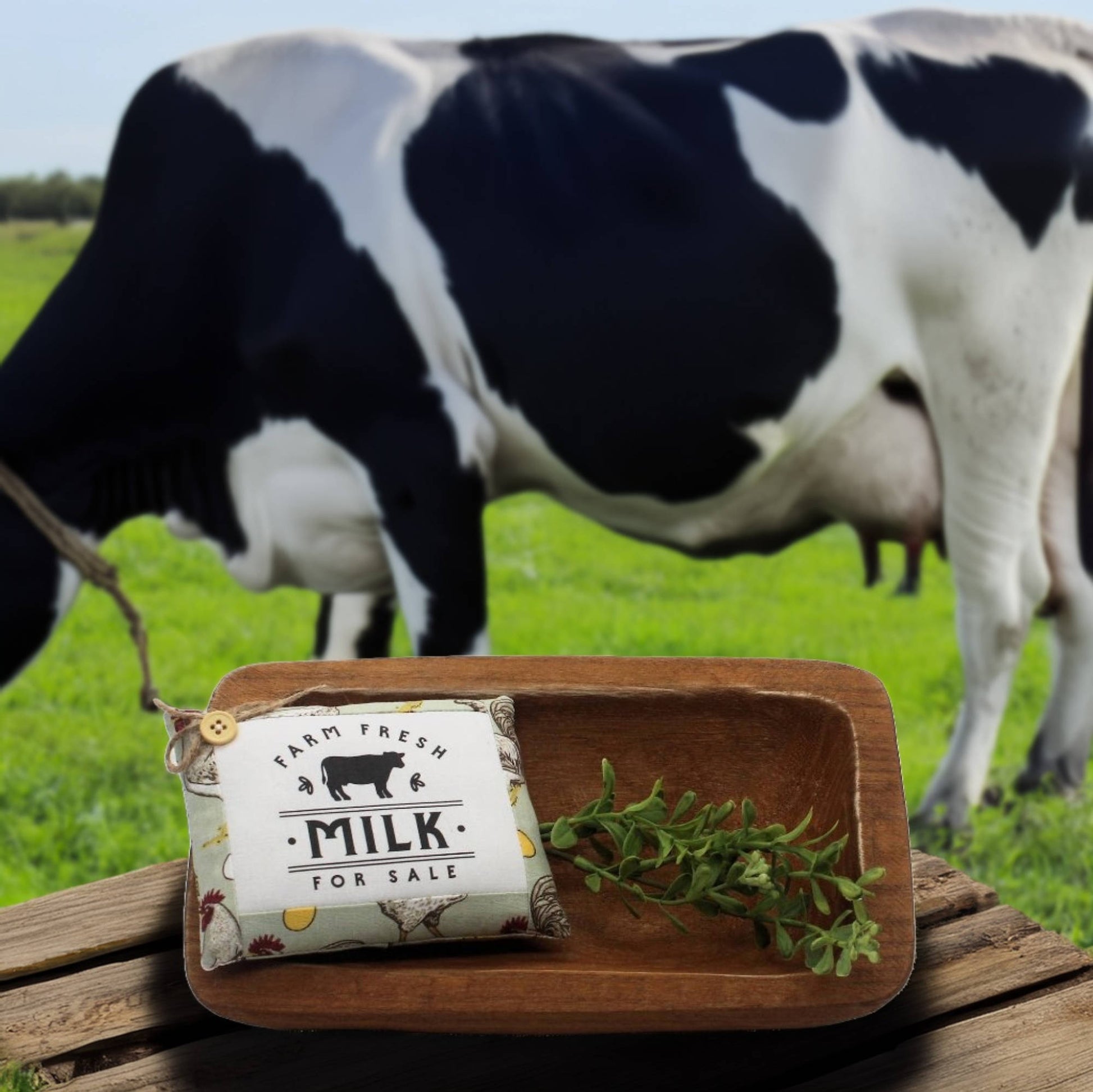 Miniature bowl filler pillow with 'Farm Fresh Milk for Sale' on a wooden board with a cow in the background.
