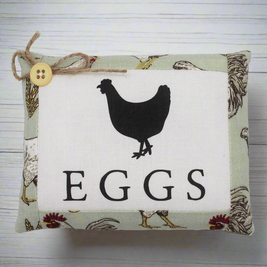 Decorative mini pillow sign with a chicken silhouette and 'EGGS' text on a fabric background.