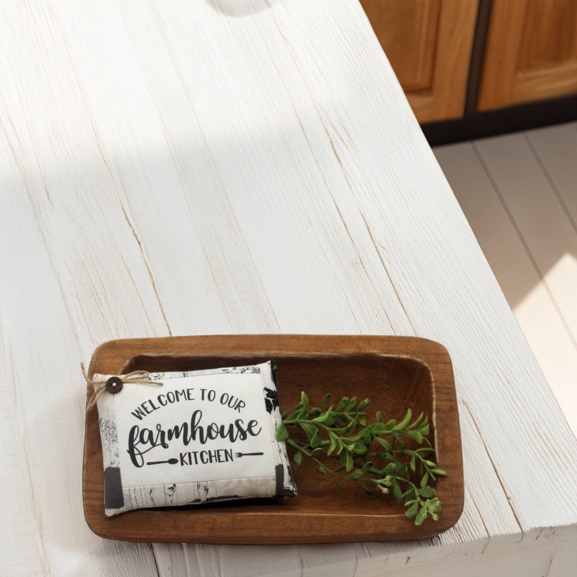 Wooden tray with a decorative bowl filler and greenery on a white surface