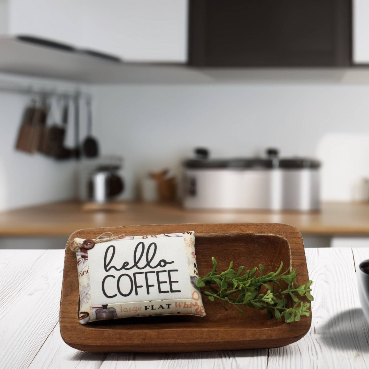 Wooden tray with a 'hello coffee' sign and greenery in a kitchen setting
