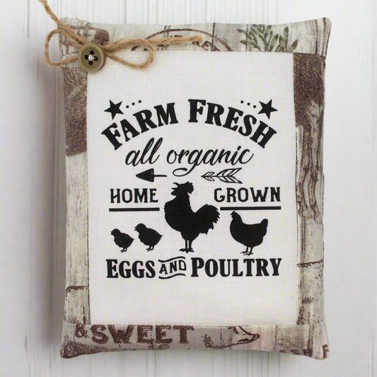 Decorative pillow tuck with 'Farm Fresh' text and chicken illustrations on a wooden background.