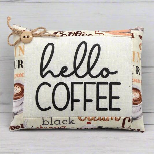 Pillow with 'hello coffee' text and coffee-themed design on a light background