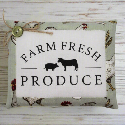 Decorative pillow tuck with 'Farm Fresh Produce' text and farm animal illustrations on a wooden background.
