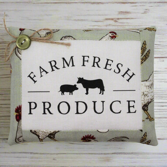 Decorative pillow tuck with 'Farm Fresh Produce' text and farm animal illustrations on a wooden background.