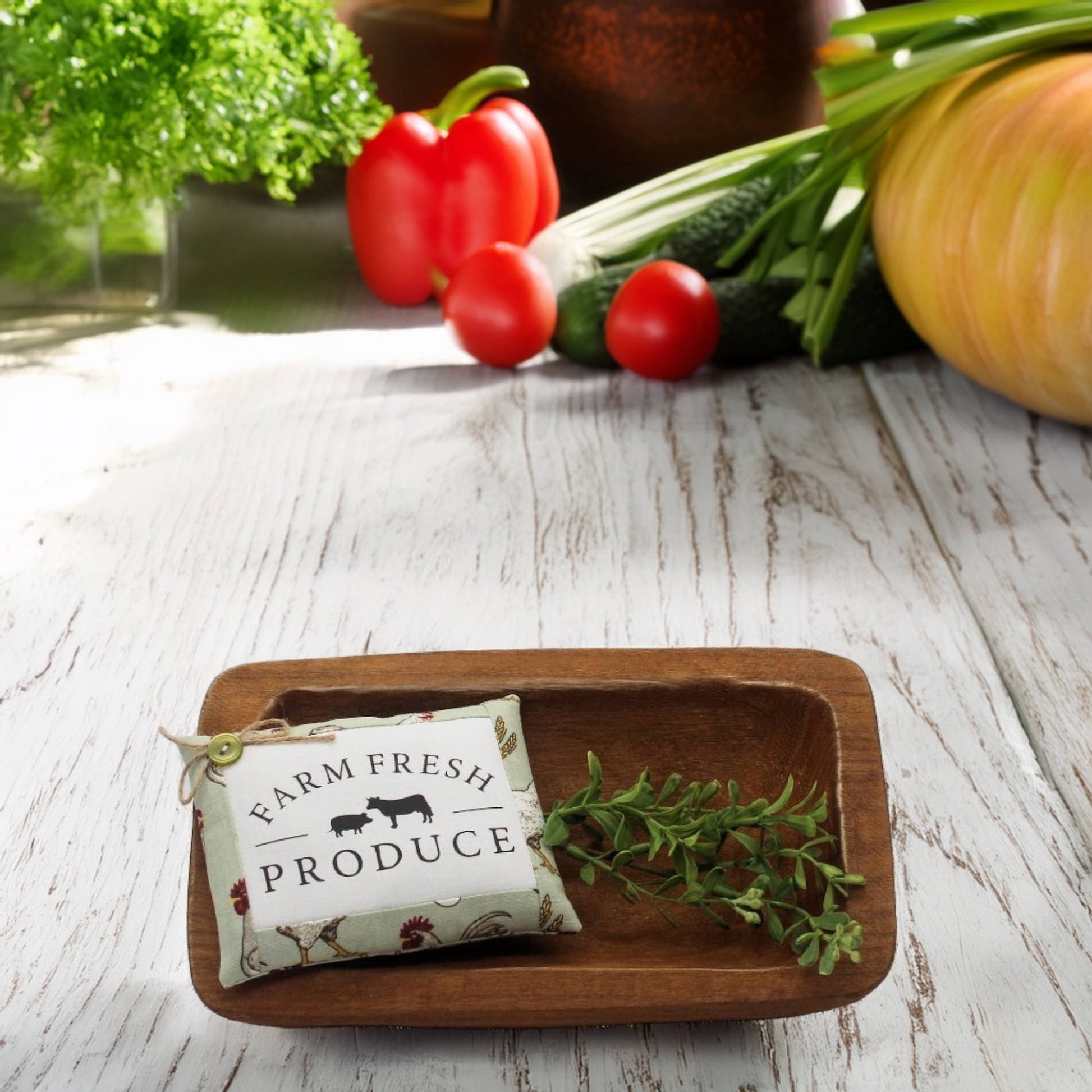 Wooden tray with a 'Farm Fresh Produce' bag and herbs on a wooden surface with vegetables in the background.