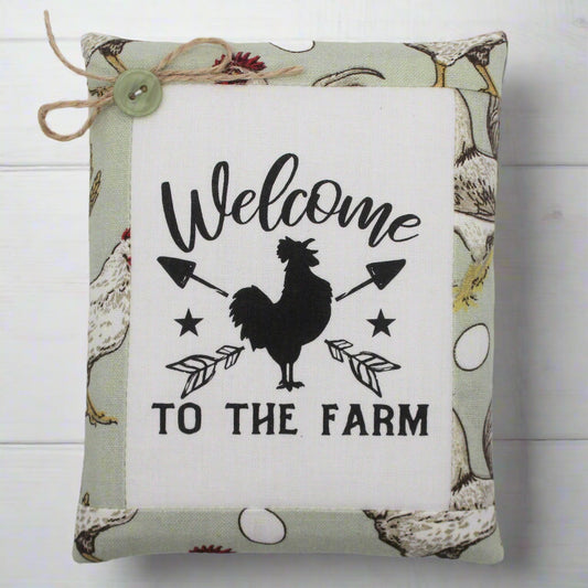 Decorative miniature pillow with 'Welcome to the Farm' text and rooster design on a white background.