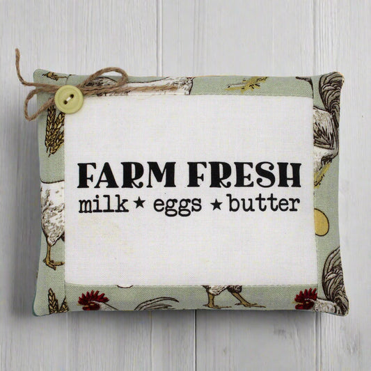 Fabric sign with 'Farm Fresh milk eggs butter' text on a wooden background