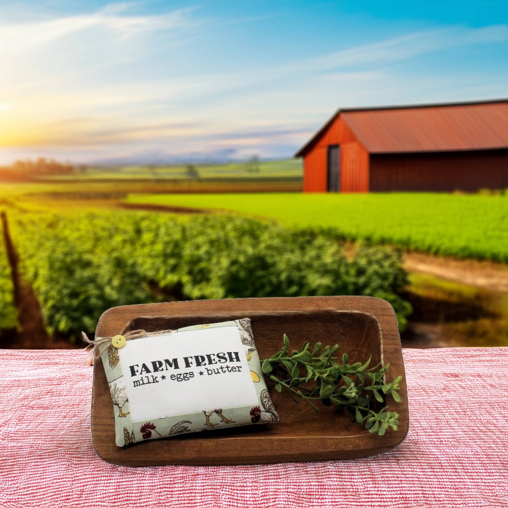 Miniature pillow bowl filler with 'Farm Fresh' label in a wooden dish on a table with a farm landscape in the background