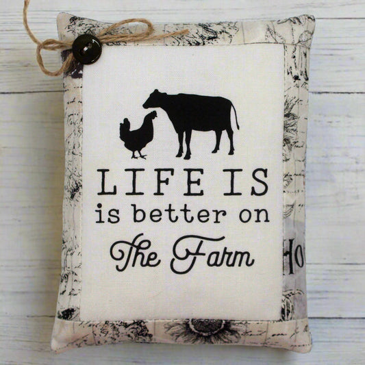 Decorative pillow tuck with farm-themed design and text on a wooden surface