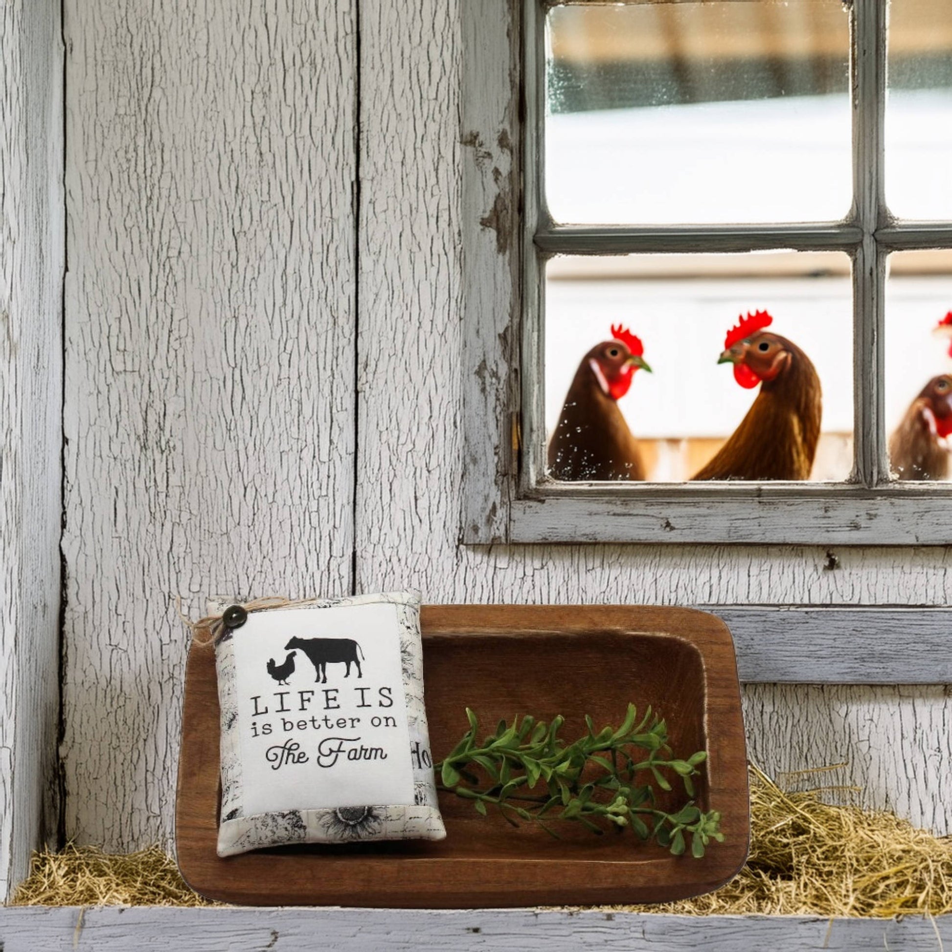 Decorative tray with a pillow and greenery in front of a window with chickens outside.