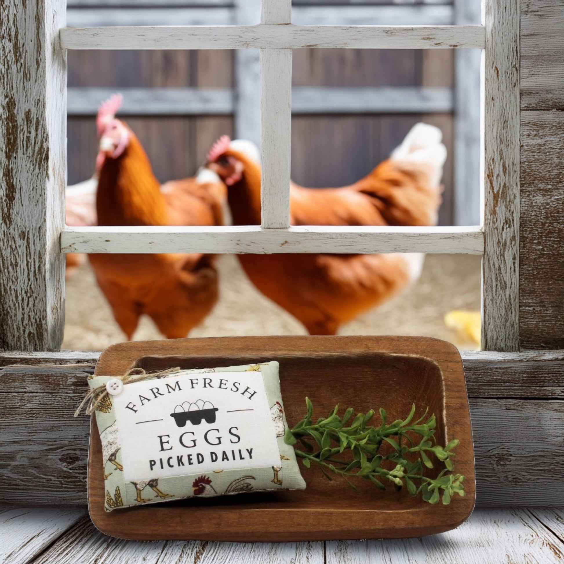 Wooden tray with 'Farm Fresh Eggs Picked Daily' pillow tuck and chickens peering through a window in the background.