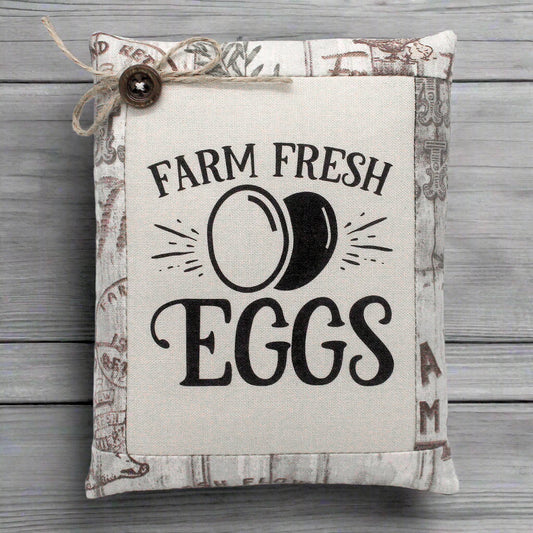 Fabric sign with 'Farm Fresh Eggs' text on a wooden background