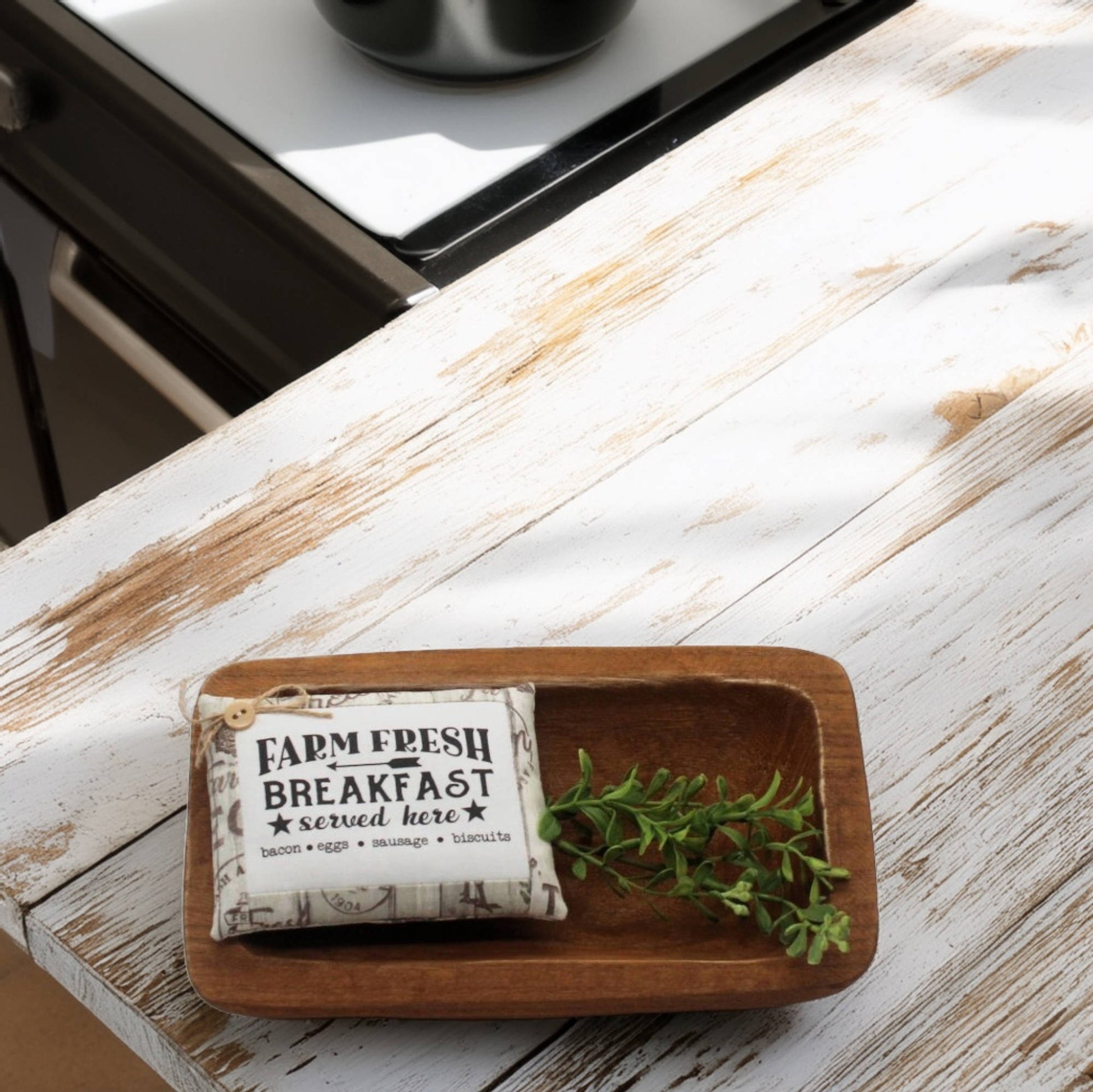 Wooden tray with a decorative pillow tuck and greenery on a wooden surface