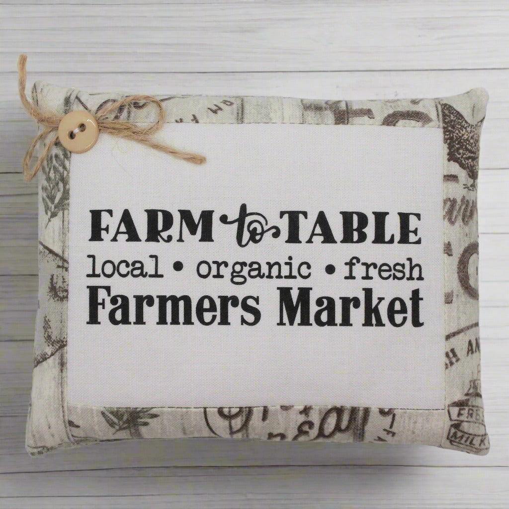 Decorative pillow tuck with 'Farm to Table' text on a wooden background