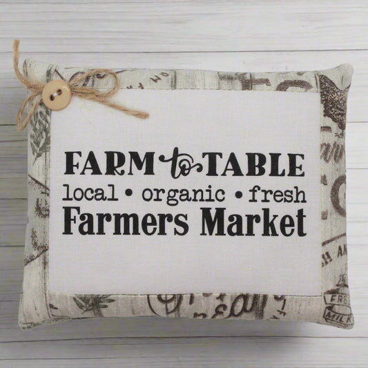 Decorative pillow tuck with 'Farm to Table' text on a wooden background