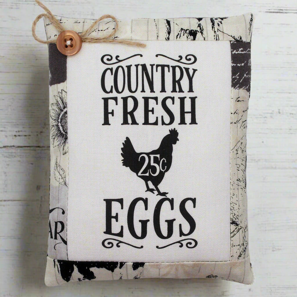 Fabric pillow tuck with 'Country Fresh Eggs' text and chicken illustration on a wooden background