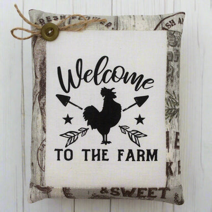 Decorative pillow tuck with a rooster design and 'Welcome to the Farm' text on a white background.