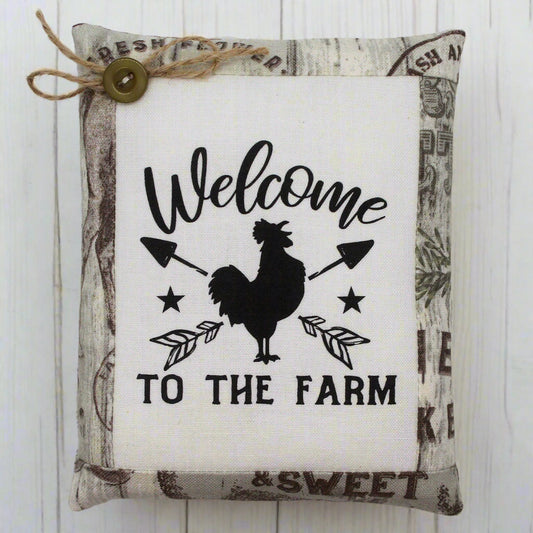 Decorative pillow tuck with a rooster design and 'Welcome to the Farm' text on a white background.