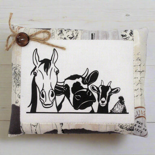 Decorative pillow tuck with black and white illustrations of farm animals on a textured background.