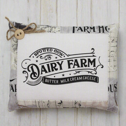Fabric mini pillow bowl filler sign with 'Dairy Farm' text on a wooden surface