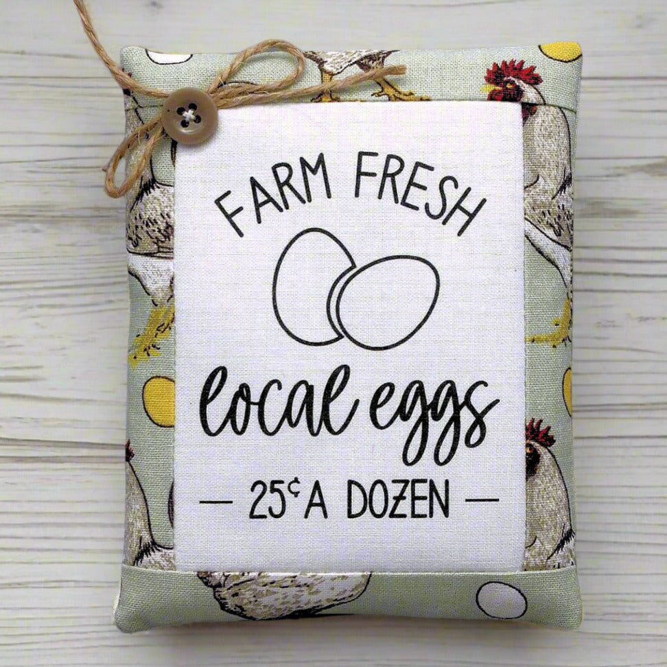 Decorative miniature pillow with 'Farm Fresh Local Eggs' text on a wooden surface