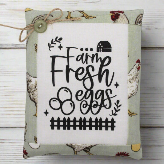 Decorative mini pillow bowl filler sign with 'Farm Fresh Eggs' text on a fabric background with chicken illustrations.