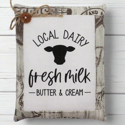 Decorative pillow tuck with 'Local Dairy, Fresh Milk, Butter & Cream' text and cow silhouette on a white background.