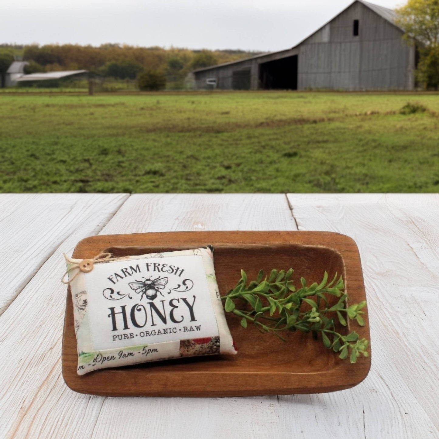 Farm fresh honey package on a wooden tray with a barn in the background