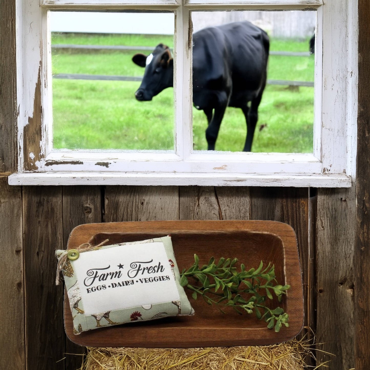 Wooden tray with a 'Farm Fresh' sign and greenery, cow visible through window in background