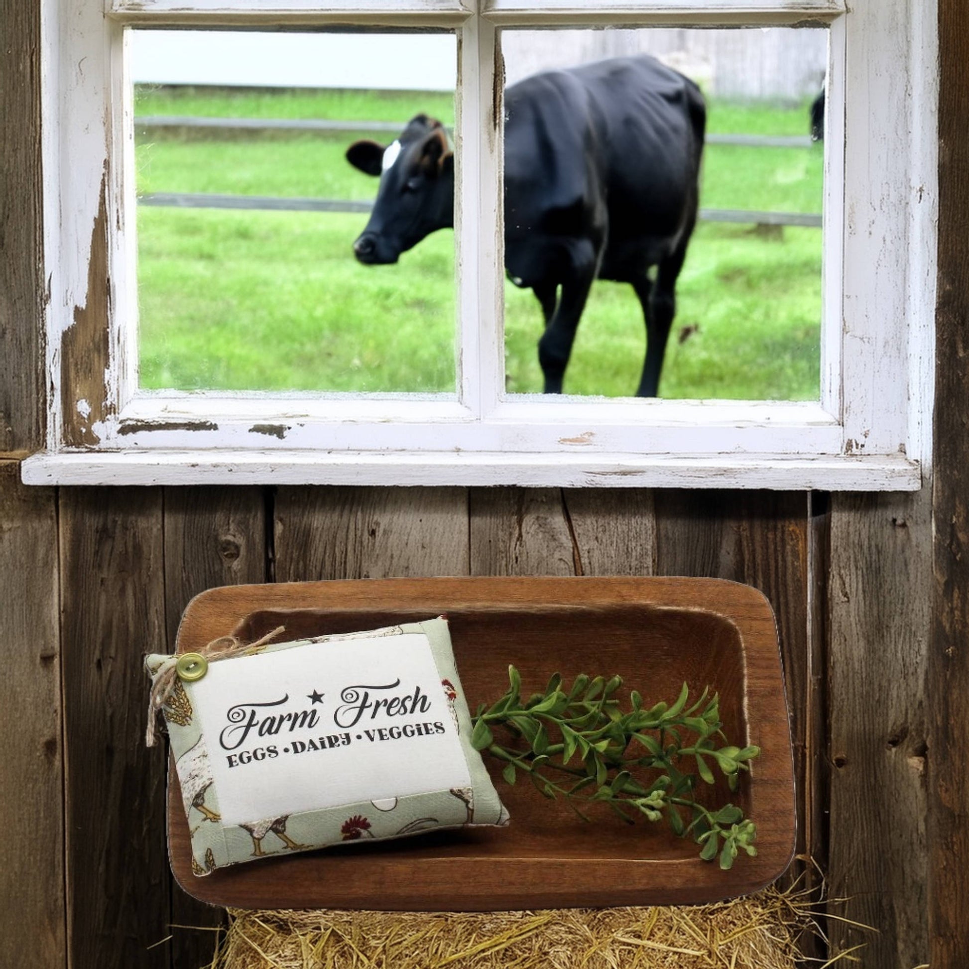 Wooden tray with a 'Farm Fresh' sign and greenery, cow visible through window in background