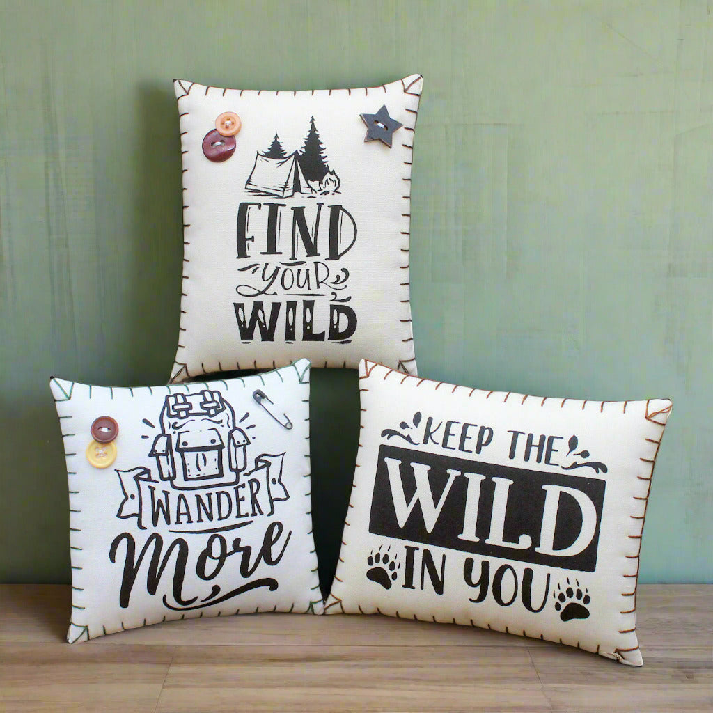 Three decorative pillows with motivational phrases on a rustic wooden background
