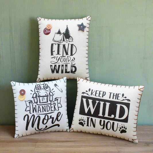 Three decorative pillows with motivational phrases on a rustic wooden background