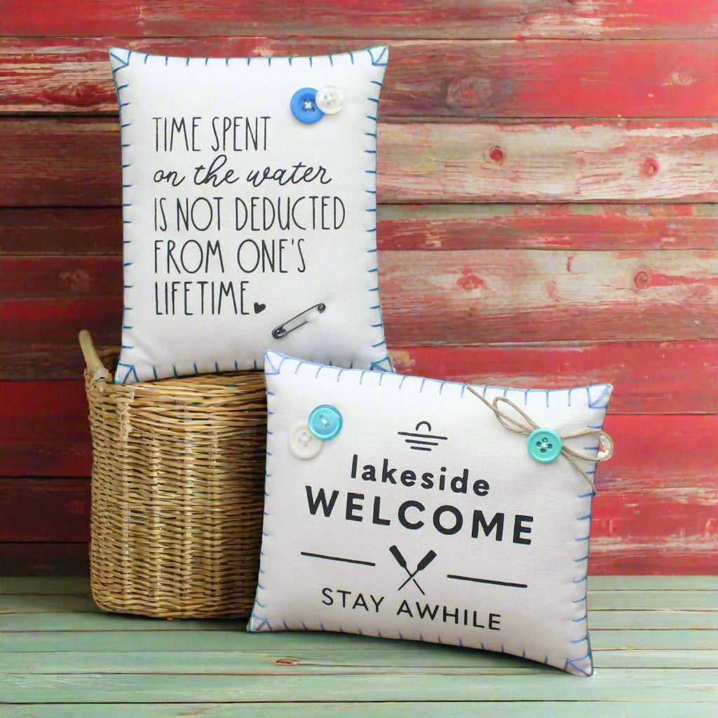Two decorative pillows with lake sayings on a rustic wooden background