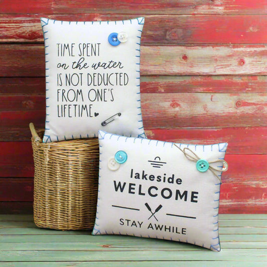 Two decorative pillows with lake sayings on a rustic wooden background