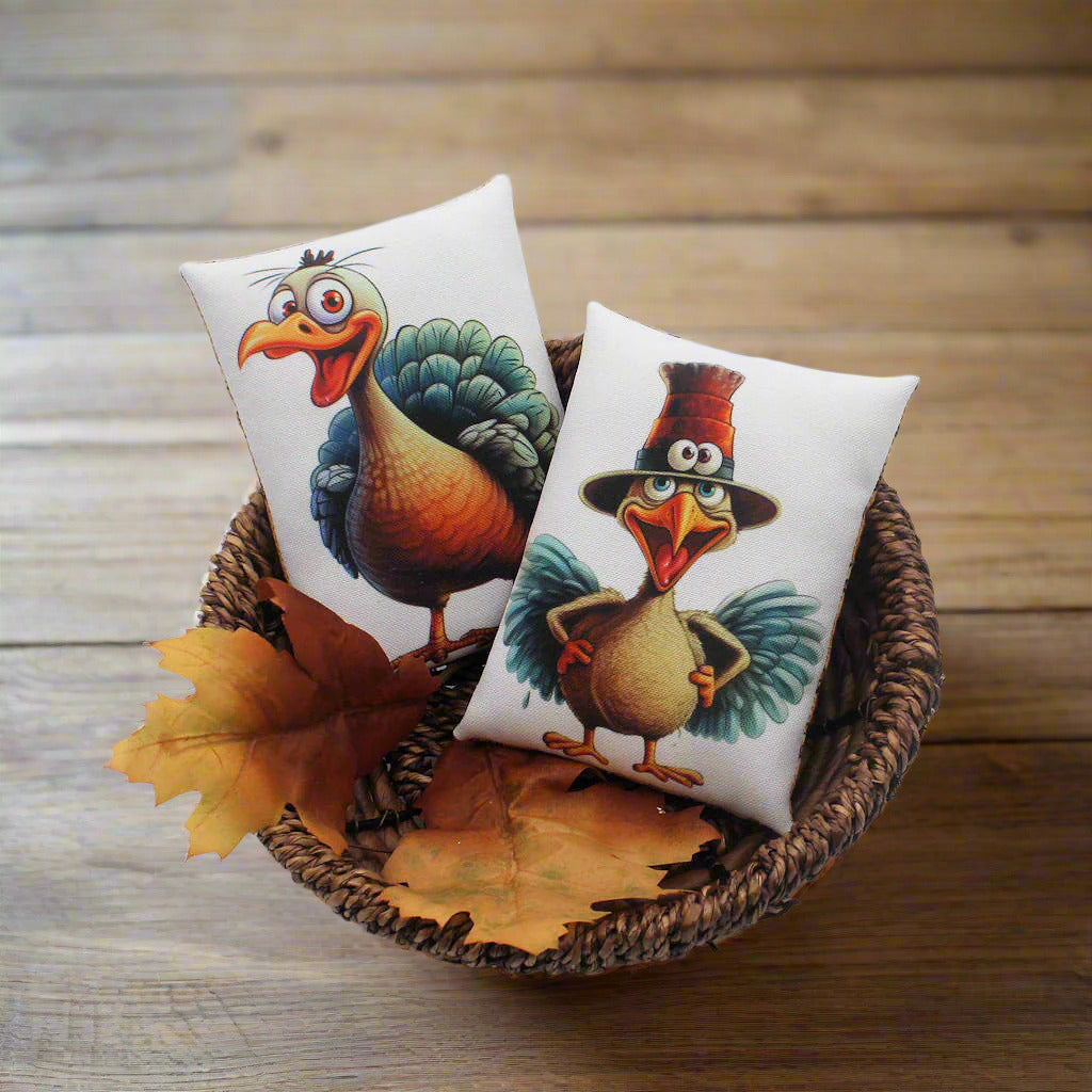 Two decorative mini pillows with cartoon turkeys in a wicker basket