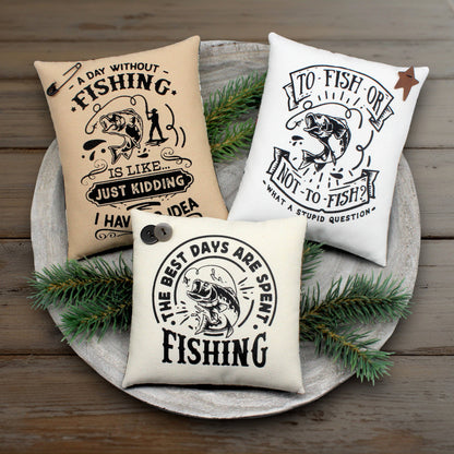 Three fishing-themed pillows on a wooden surface with greenery.