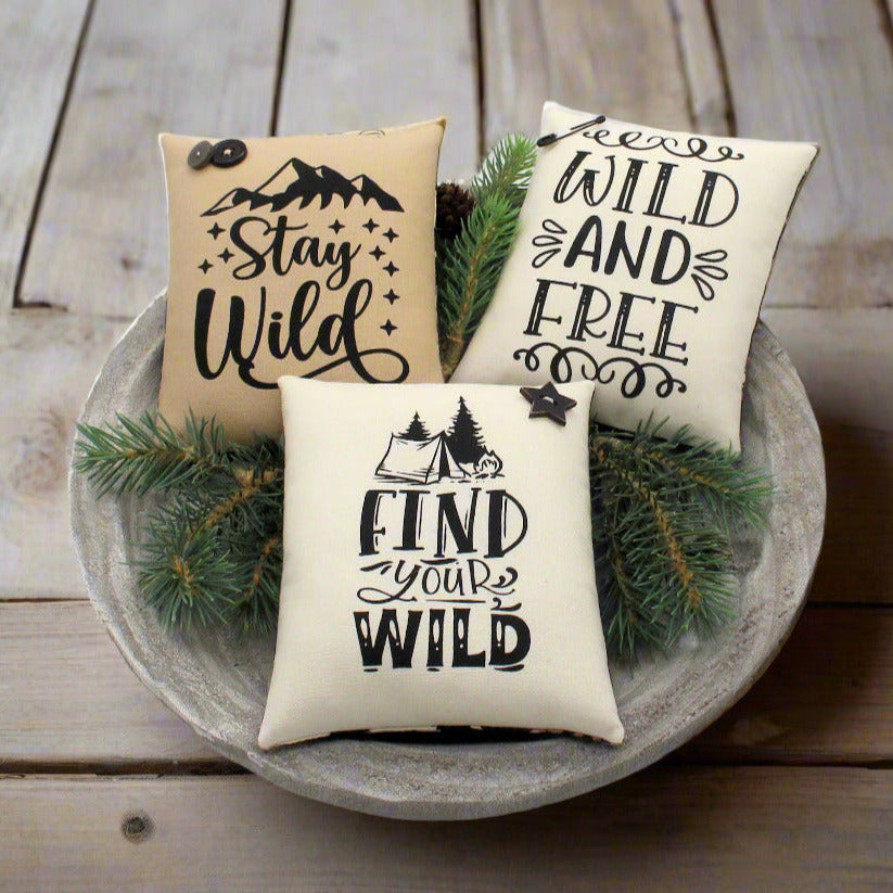 Three pillows with motivational phrases on a decorative tray with greenery
