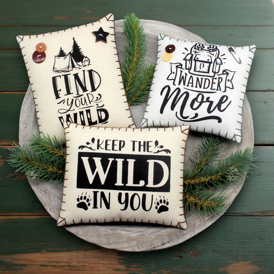 Three decorative pillows with motivational phrases on a wooden surface.