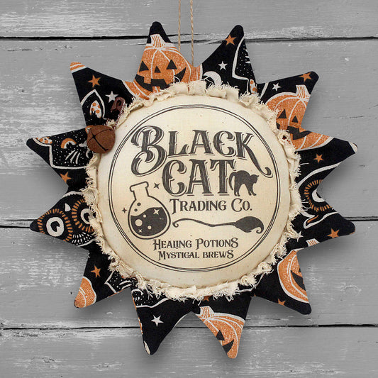 Primitive handmade fabric sunflower ornament for Halloween with a printed center that advertises for the Black Cat Trading Company