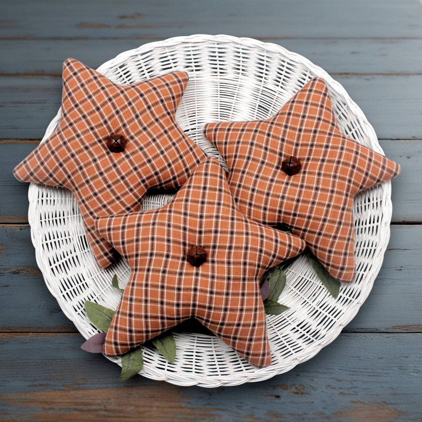 Set of three light brown checkered homespun fabric stars with rusty bells in their centers