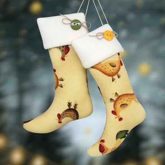 Two Christmas stocking ornaments with white fleece cuffs and hanging strings, decorated with folk art chickens and colorful buttons, set against a blurred festive background.