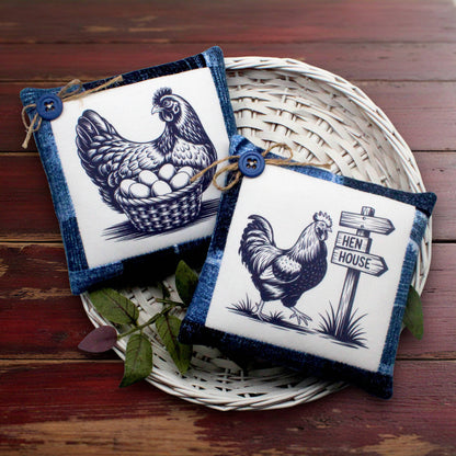 Two square decorative pillows with denim blue borders and white center panels featuring black chicken illustrations, displayed on a white woven tray over a dark wooden surface.