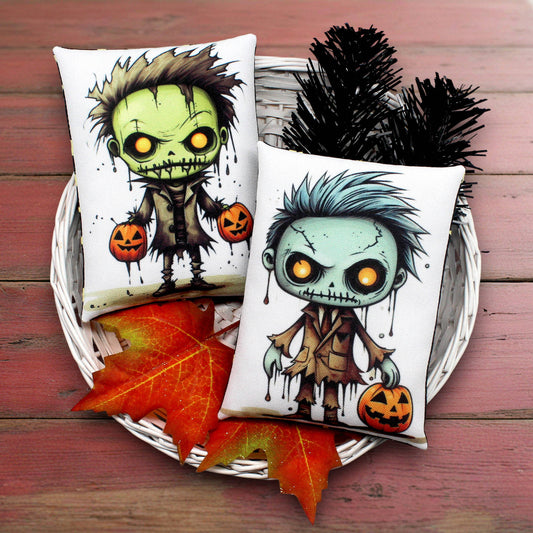 Two Halloween-themed pillows with cartoon character cute zombies on a wooden surface with autumn leaves.