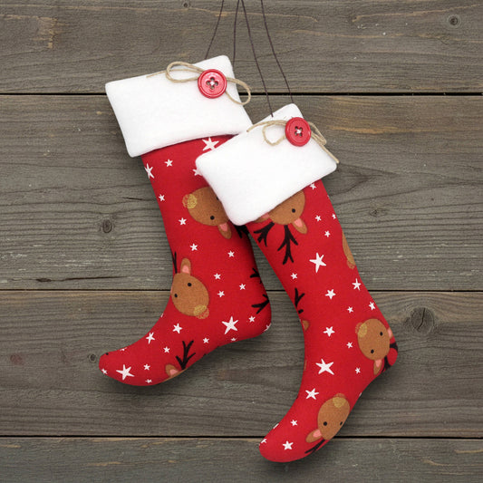 Pair of handmade Christmas stocking ornaments with cute reindeer on a red fabric background.