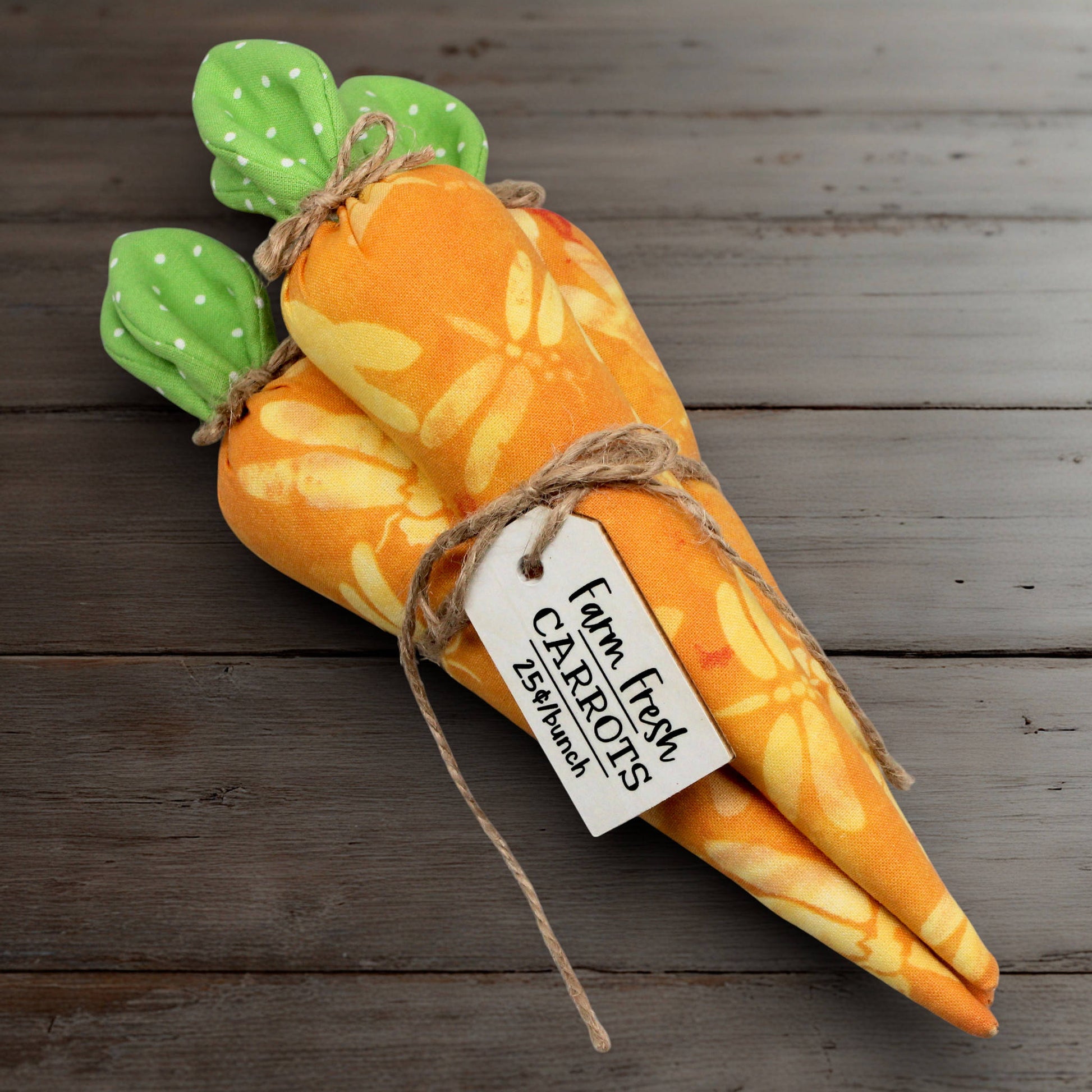 Plush carrot bundle with green top on a wooden surface, featuring a 'Farm Fresh Carrots' tag.
